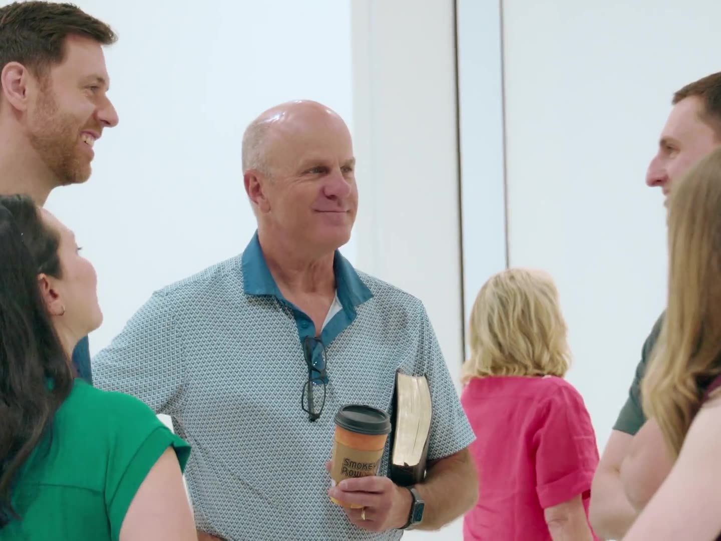 People greeting each other before the service, coffee and Bible in hand